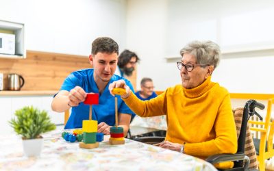 Nurse and senior woman stacking colorful wooden blocks, engaging in recreational therapy at a nursing home